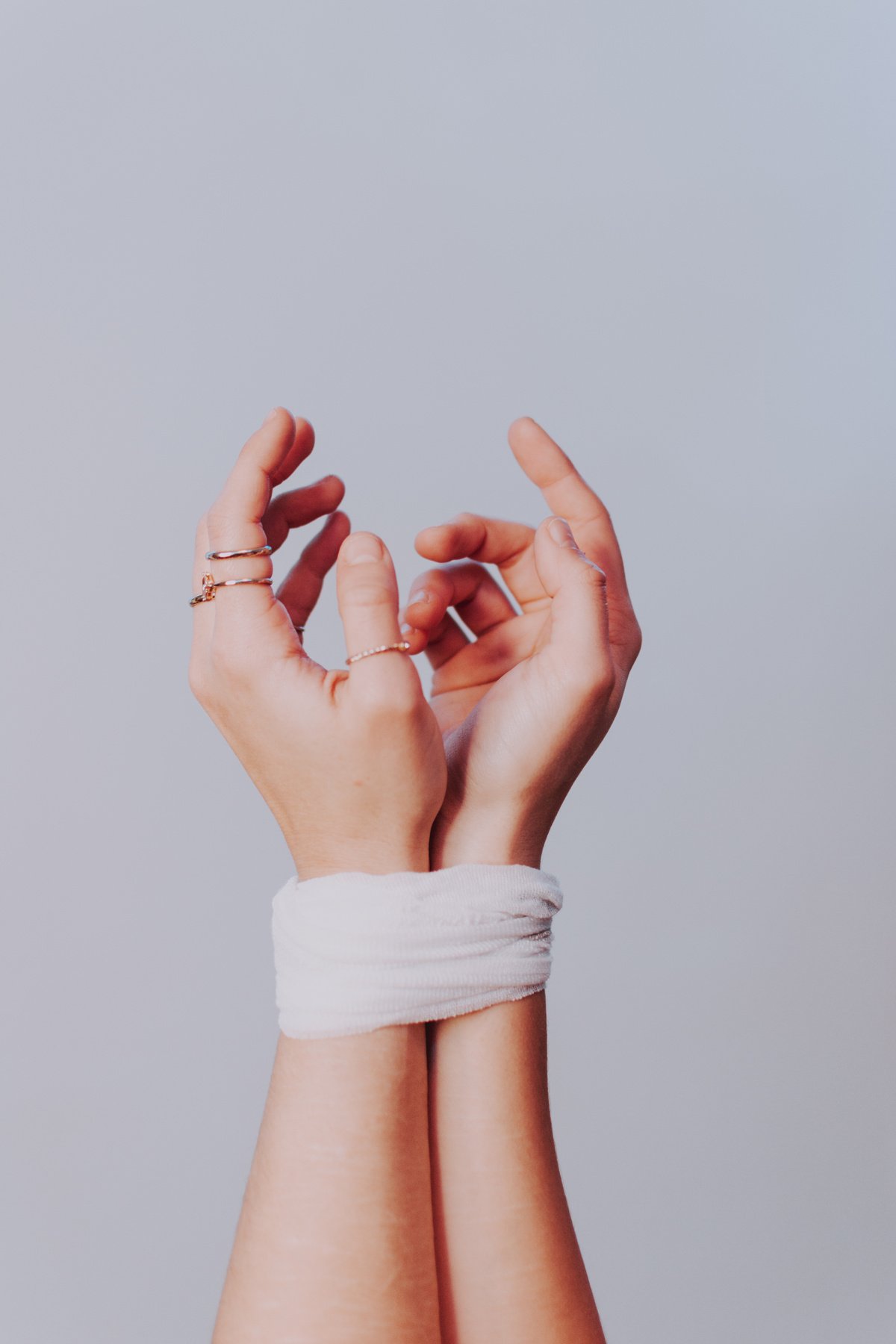 Anonymous woman with tied hands against gray background